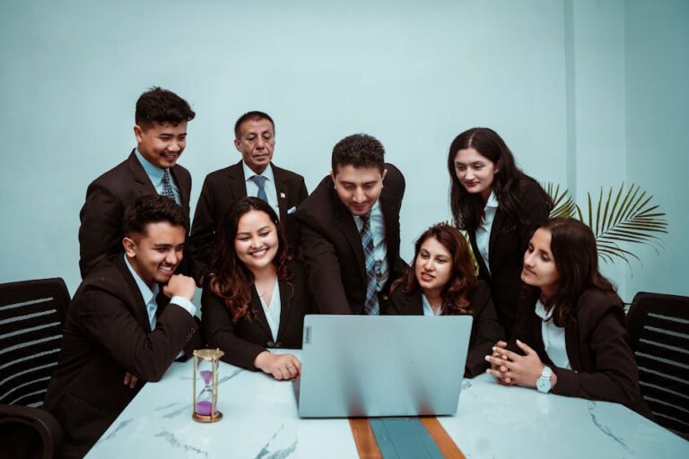 A diverse team of professionals collaborating around a laptop in a modern office setting.